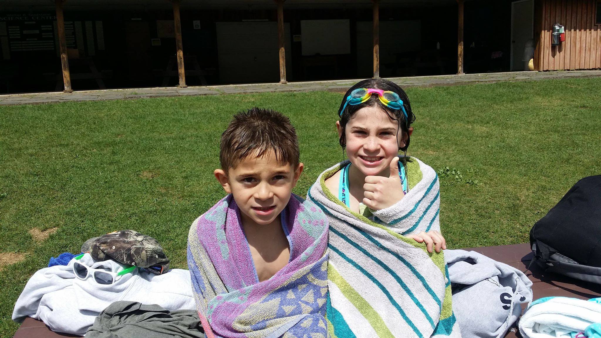 Two kids wrapped in towels after swimming